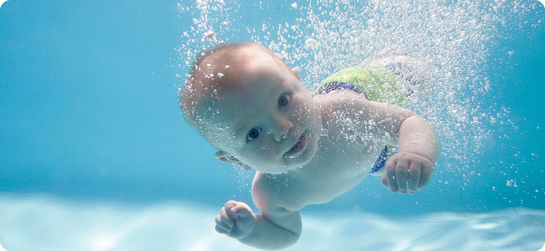 Baby swimming underwater with bubbles